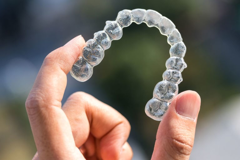 Hand holding Invisalign clear aligners