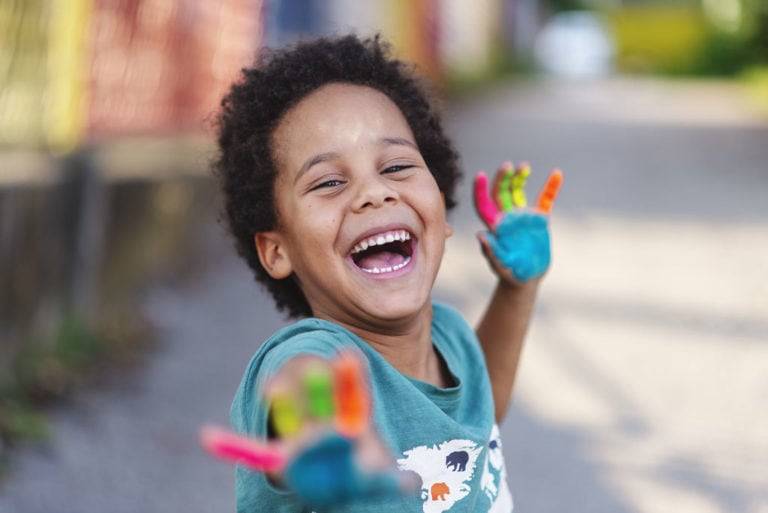 Happy boy with painted hands smiling at Behl Orthodontics