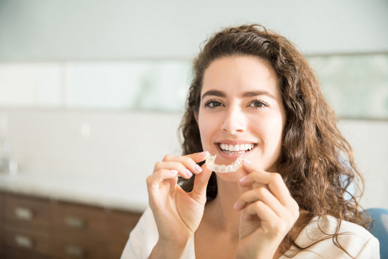 Woman putting in her Invisalign aligners at Behl Orthodontics